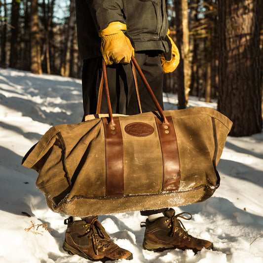 Person carrying a waxed canvas and leather log carrier.