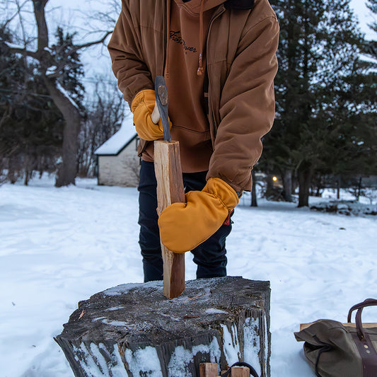 Chopping wood with handcrafted buckskin mittens in winter.