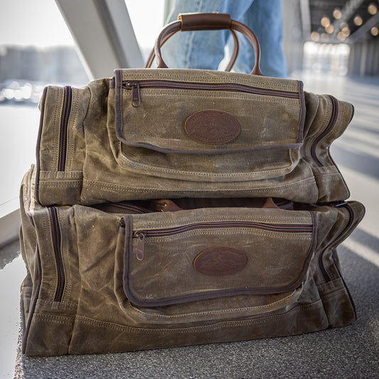 Two sizes of the premium waxed canvas duffel bags known as the Laurentian Luggage Bag sitting on top one another.