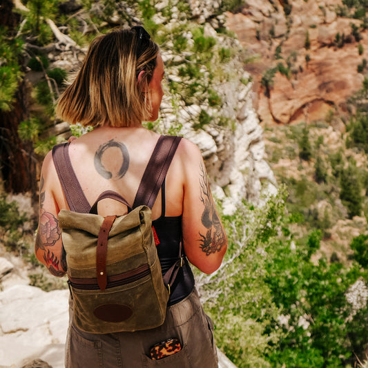 A woman hiking while wearing a smaller rolldown waxed canvas daypack.
