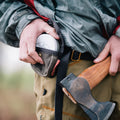 A man taking an axe sharpening puck out of his waxed canvas belt pouch. 