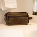 Waxed Canvas and leather travel kit sitting next to a sink. 