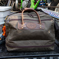Frost River's waxed canvas and leather Prairie Boot Bag sitting in the back of a pickup truck with a dirt bike.  