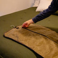 A person zipping his suit up into a waxed canvas garment cover. 