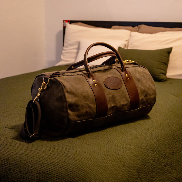 The small ImOut Duffel Bag by Frost River packed up and sitting on a bed ready to go. 