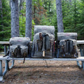 Frost River's three different sized Isle Royale Bushcraft Packs sitting next to each other on a campsite bench. 
