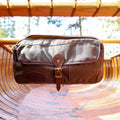 A waxed canvas and leather Thwart Bag hanging in a cedar strip canoe ready to kit the river. 