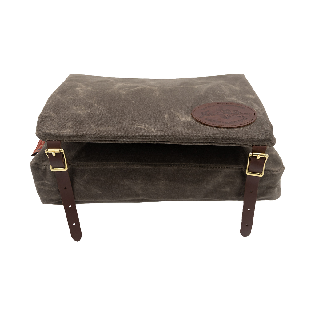 A waxed canvas canoe seat pad that has an attached bag that hangs underneath the canoe seat. 