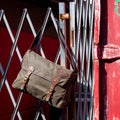 Handmade messenger bag hang on a gate. 