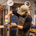 A man wearing a waxed canvas shop apron in a wood shop