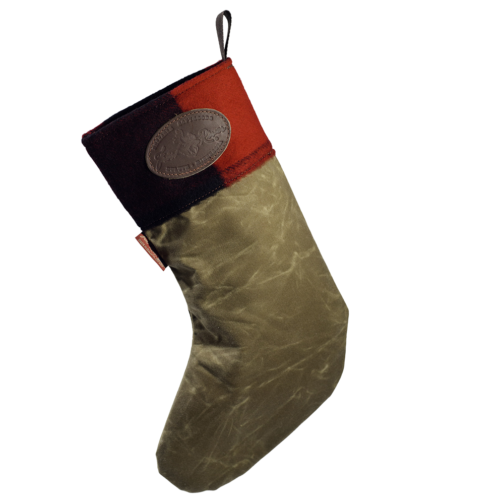 A Christmas stocking with a textured olive green body, a red and patchwork cuff, and a brown leather logo patch on the side.