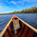 A cedar strip canoe paddling a lake with a waxed canvas Bow Bag crafted in Duluth, Minnesota by Frost River
