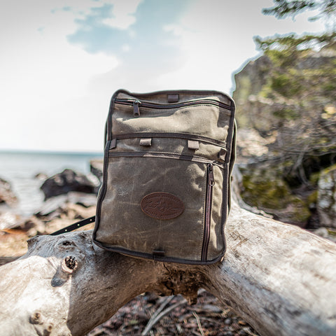 Waxed canvas Itasca pack sitting on a log on the edge of Lake Superior