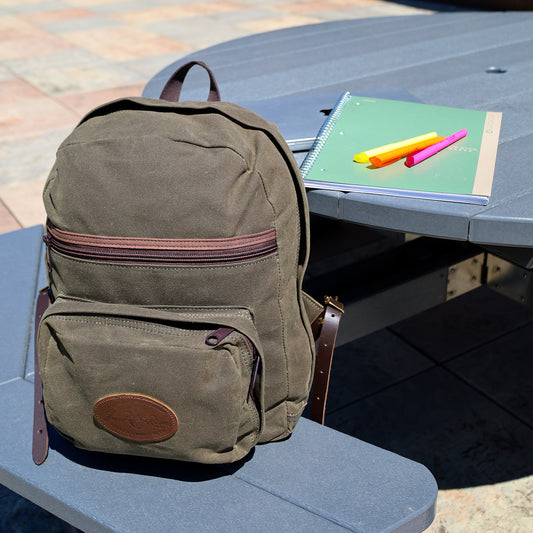 Frost River's North Bay Backpack sitting at a park bench with a notebook and highlighters. 