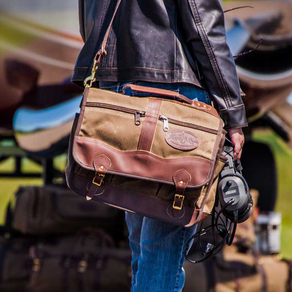 A person carrying a brown leather and waxed canvas briefcase. 