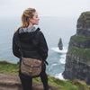 A woman wearing a shell shaped waxed canvas and leather shoulder bag. 