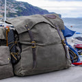 A traditional style waxed canvas canoe pack sitting in the harbor in front of a line of boats. 