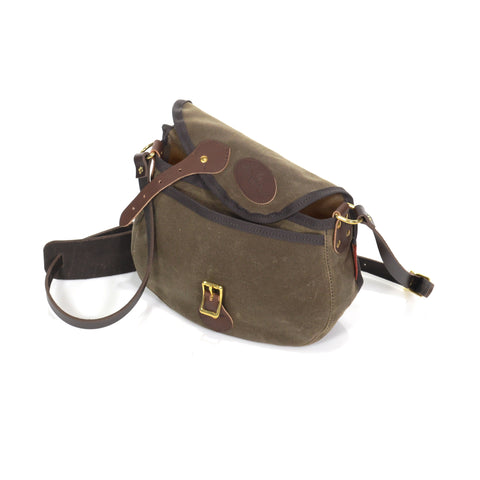 The Shell Bag is closed with a waxed canvas flap, leather strap, and solid brass buckle.