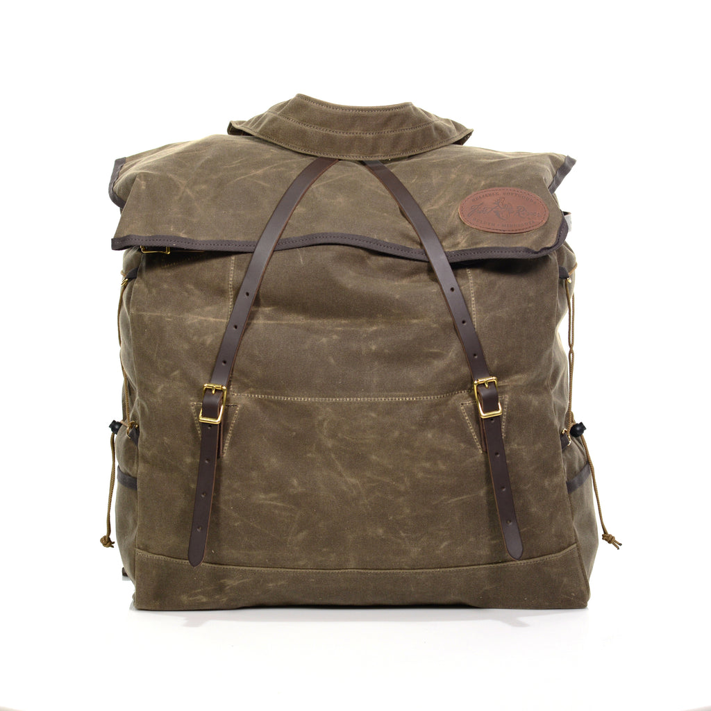 The Grand Portage Canoe Pack has a closure flap lined with cotton binding and secured with two crossing premium leather straps connected to solid brass buckles on the lower part of the pack.
